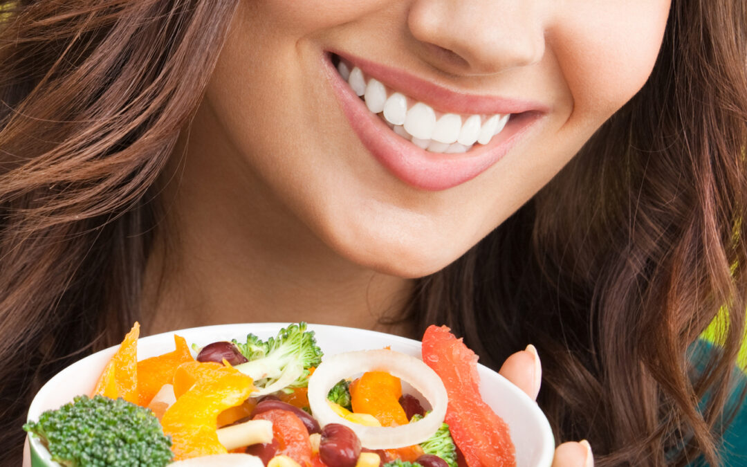 Woman smiles while holding a bowl of salad