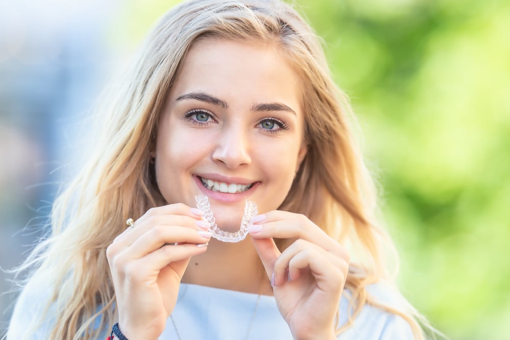 Teen holding invisalign clear braces tray