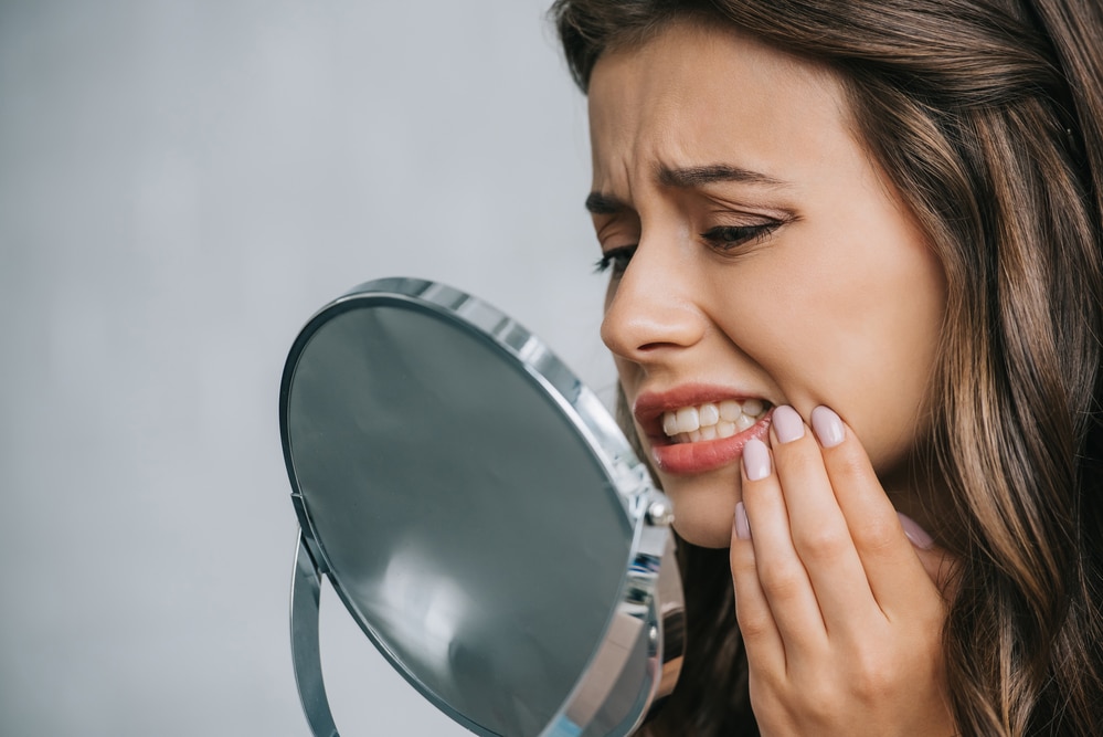 woman looking at teeth in mirror needs family dentist