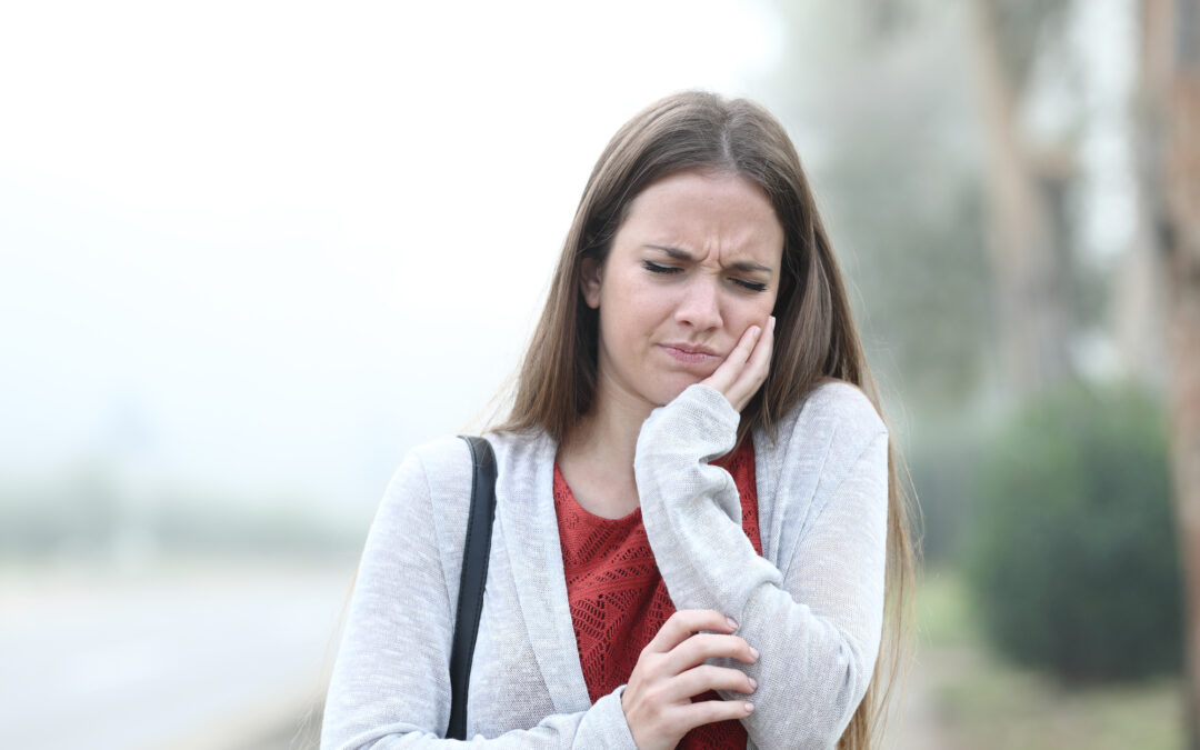 woman with a toothache holding her face while walking