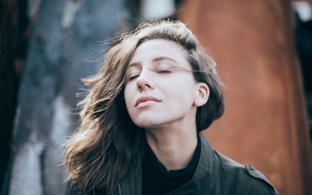 woman with head tilted up and eyes closed as wind blows through her hair