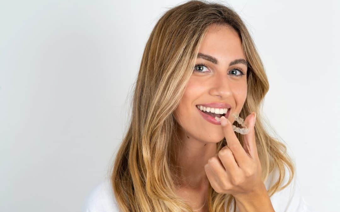 blonde woman putting invisalign clear aligners in mouth