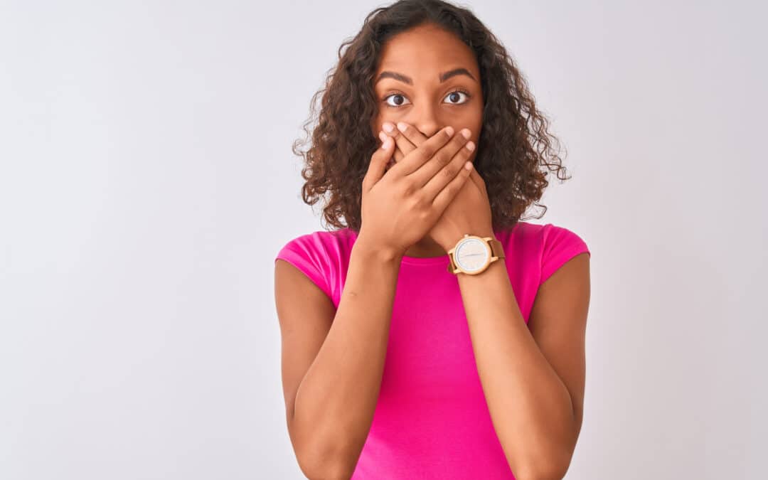 woman in pink shirt covering her mouth because of an embarrassing smile