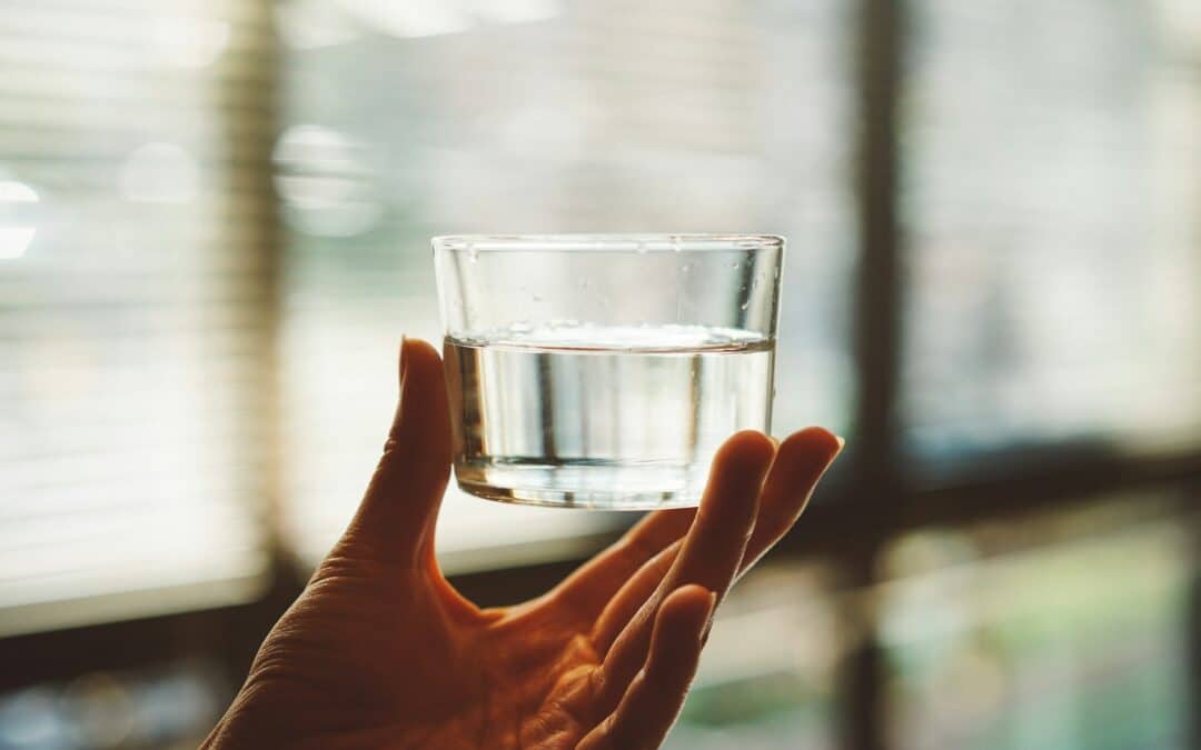 close up of hand holding small glass of water